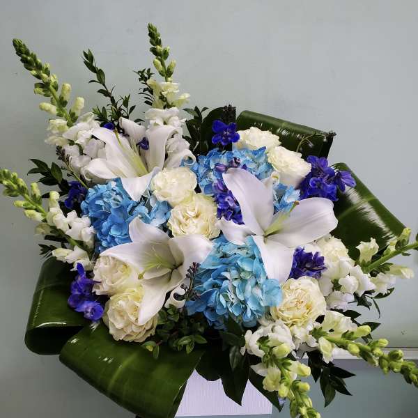 Blue and white floral arrangement with lilies and roses