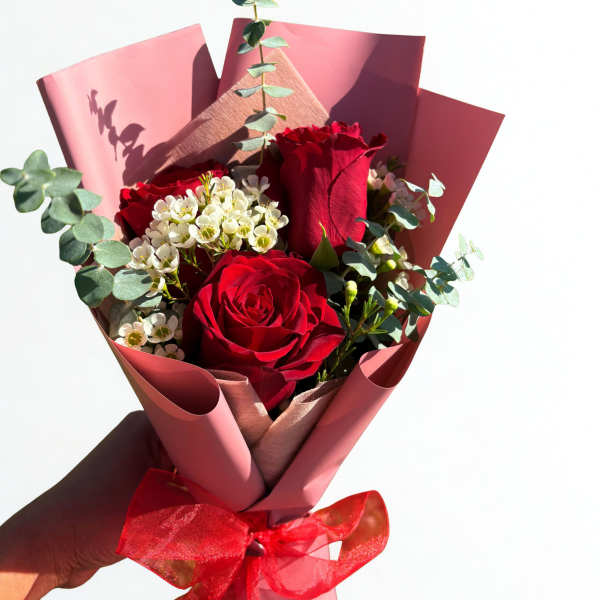 Bouquet of red roses with white filler flowers and pink wrapping