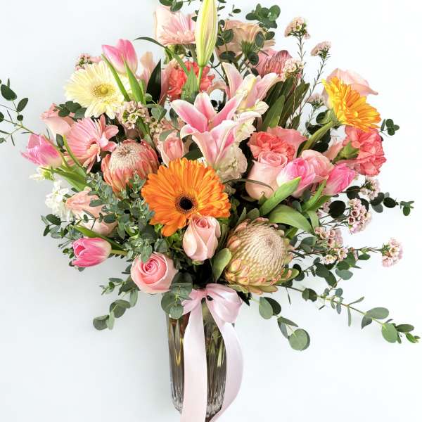 Pink and peach mixed bouquet in a glass vase with a ribbon