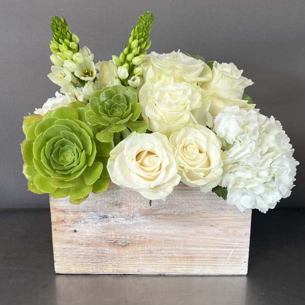 White roses and green succulents in a rustic wooden box