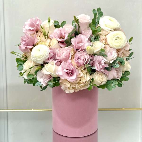 Pink and white roses with ranunculus in a pink hat box
