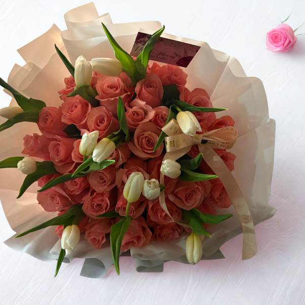 Bouquet of pink roses with white tulips wrapped in cream paper