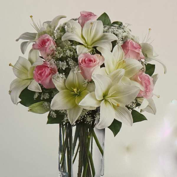 Pink roses and white lilies in a clear glass vase