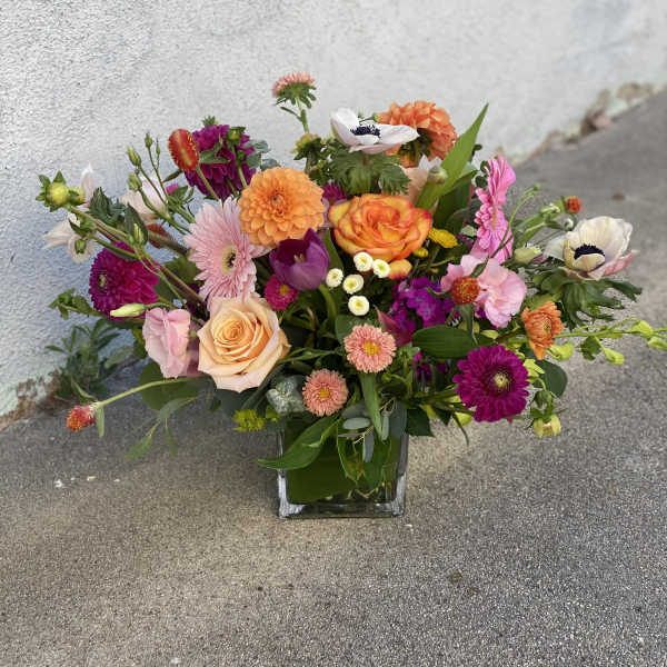 Mixed bouquet of colorful flowers in a square glass vase