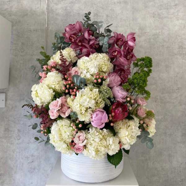 Large mixed bouquet in a white ribbed vase with pink and white blooms