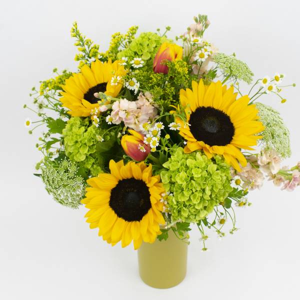 Sunflower bouquet with green hydrangeas and small white flowers in a vase