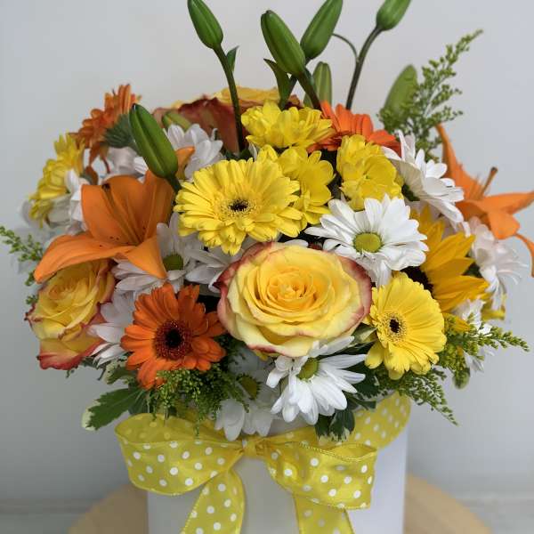 Yellow and orange mixed bouquet in a white hat box with a polka-dot ribbon