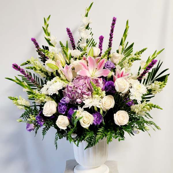 Large bouquet of pink lilies, white roses, and purple flowers in a white vase