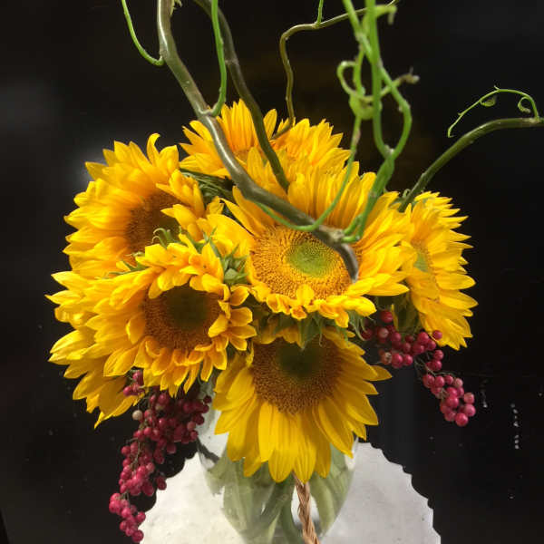 Bouquet of yellow sunflowers with curly green stems and pink berries