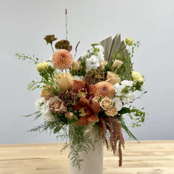Peach and white floral arrangement in a white vase