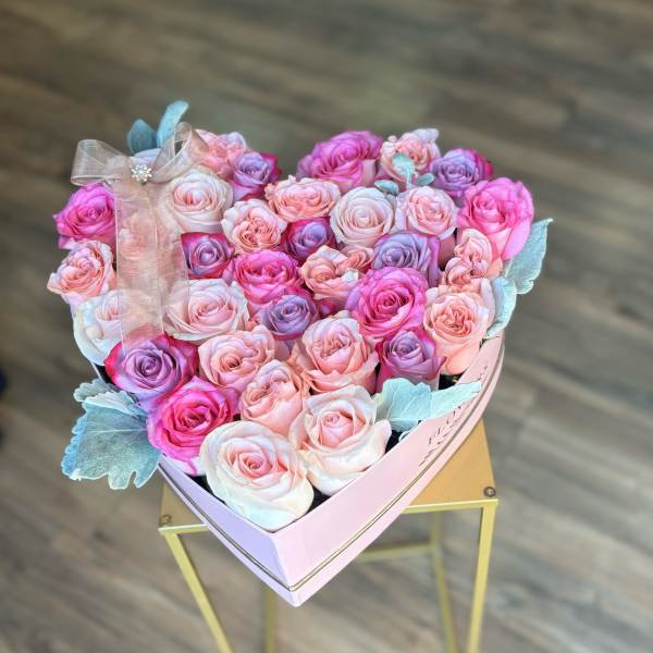 Heart-shaped box of pink and lavender roses with a ribbon bow