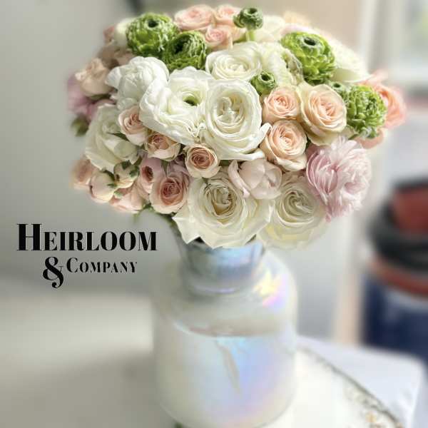 Bouquet of white, blush, and green flowers in a glass vase