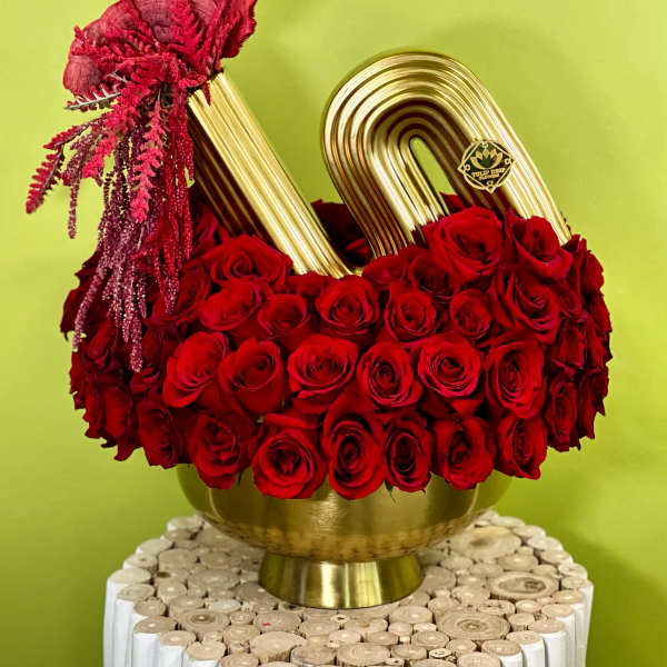 Red roses arranged in a gold vase with a gold handle accent