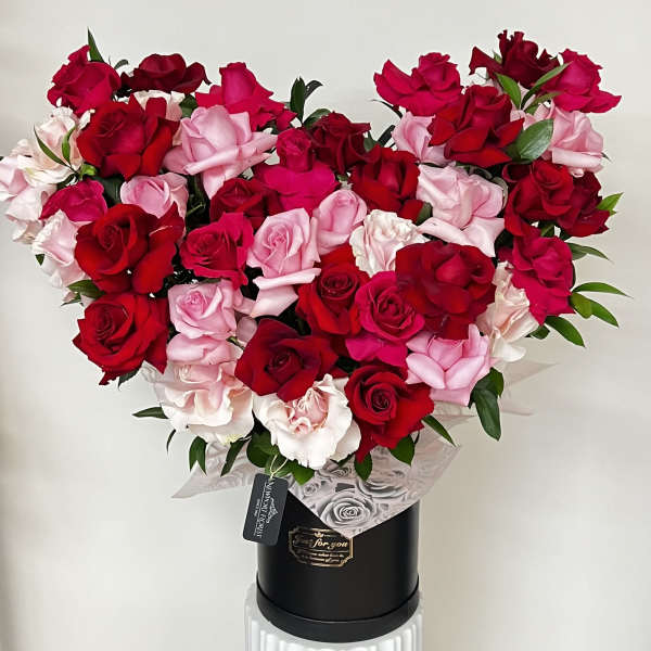 Heart-shaped bouquet of red and pink roses in a black box