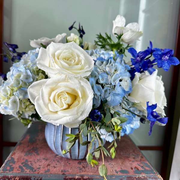 White roses and blue hydrangeas in a striped vase