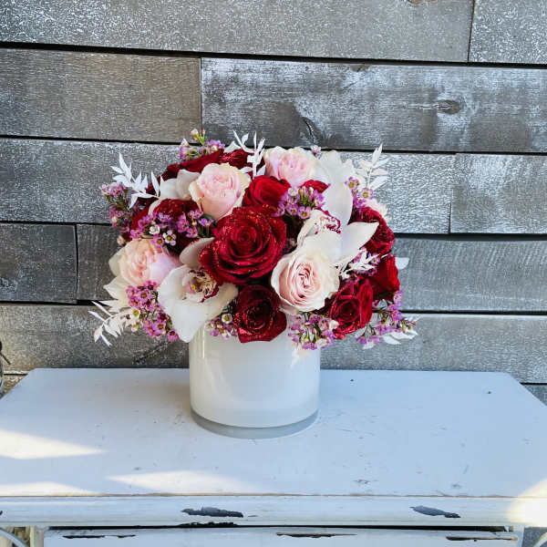 Red and blush roses arranged in a white vase