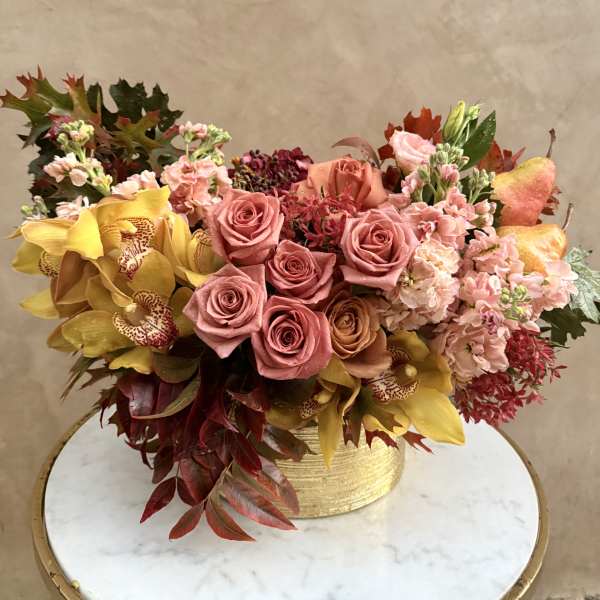 Mixed bouquet of pink roses and yellow orchids in a gold vase