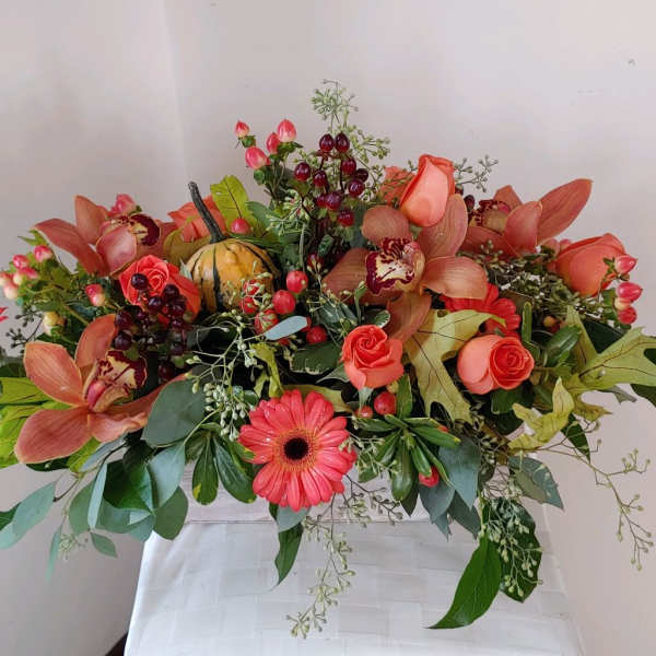 Coral floral arrangement with roses, orchids, and a gerbera daisy