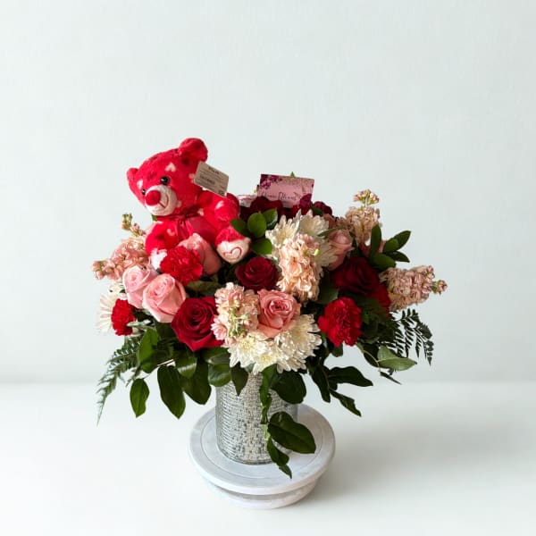 Bouquet of red and pink roses with a red teddy bear in a silver vase