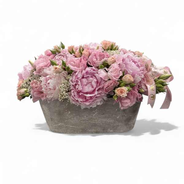 Pink floral arrangement in a gray rectangular container with a ribbon