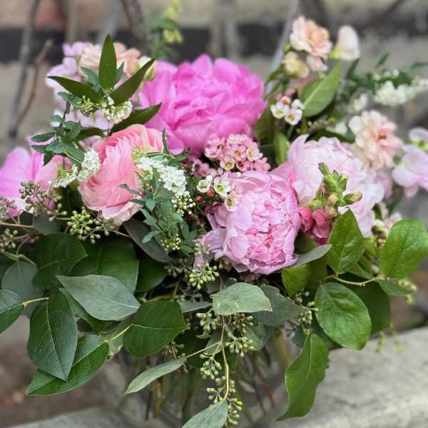 Pink peonies and roses in a loose bouquet with greenery