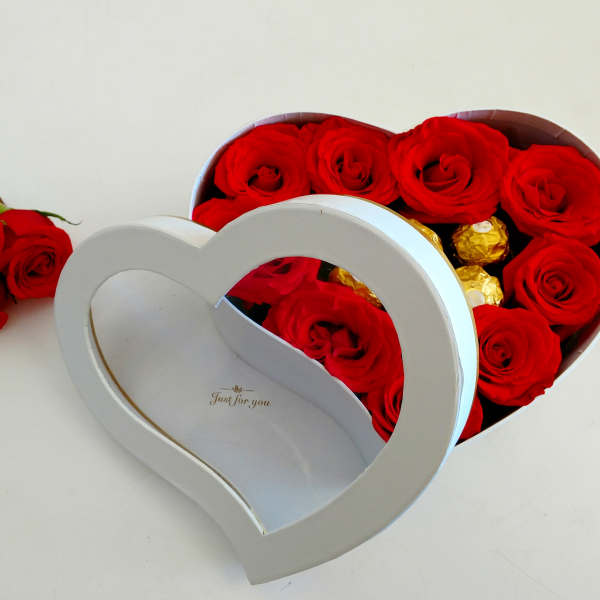 Red roses in a heart-shaped gift box with gold chocolates