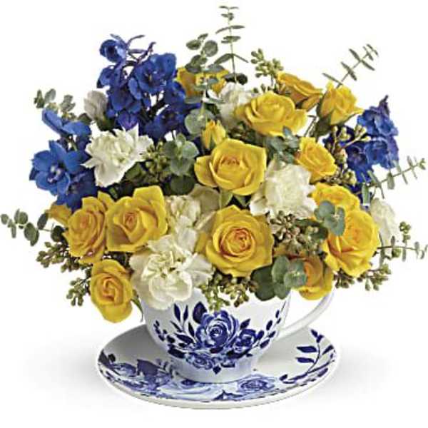 Yellow and blue rose bouquet in a teacup and saucer