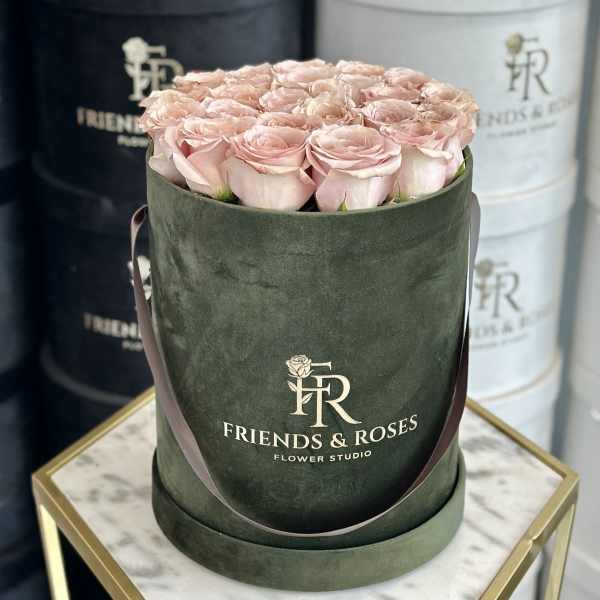 Pink roses arranged in a dark green hat box