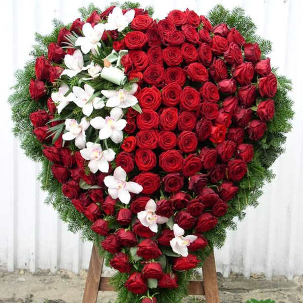 Heart-shaped wreath of red roses with white orchids on an easel