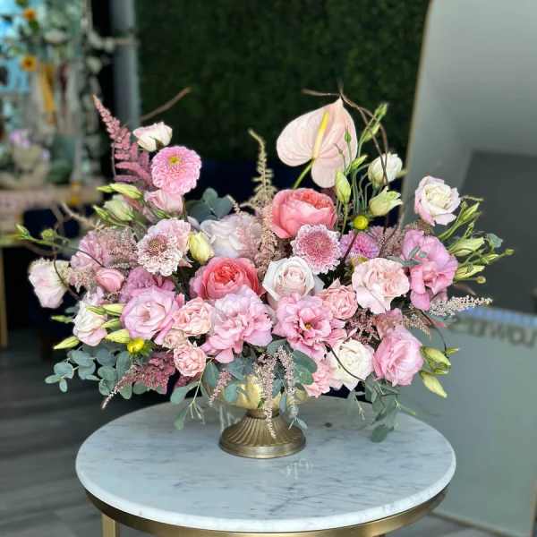 Pink and white floral arrangement in a gold pedestal vase