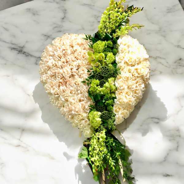 Heart-shaped bouquet of cream roses with green flowers and trailing greenery