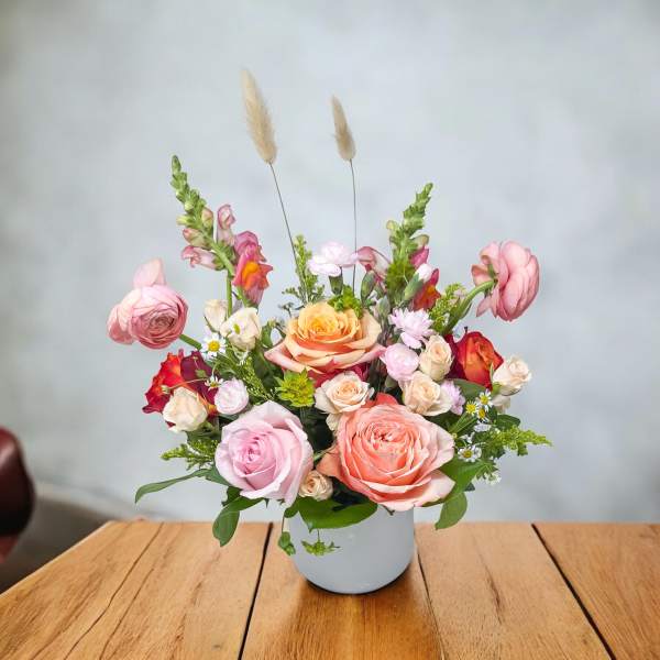 Mixed pink and peach flower arrangement in a white vase