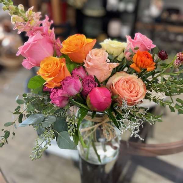 Mixed bouquet of pink, orange, and peach roses in a glass vase