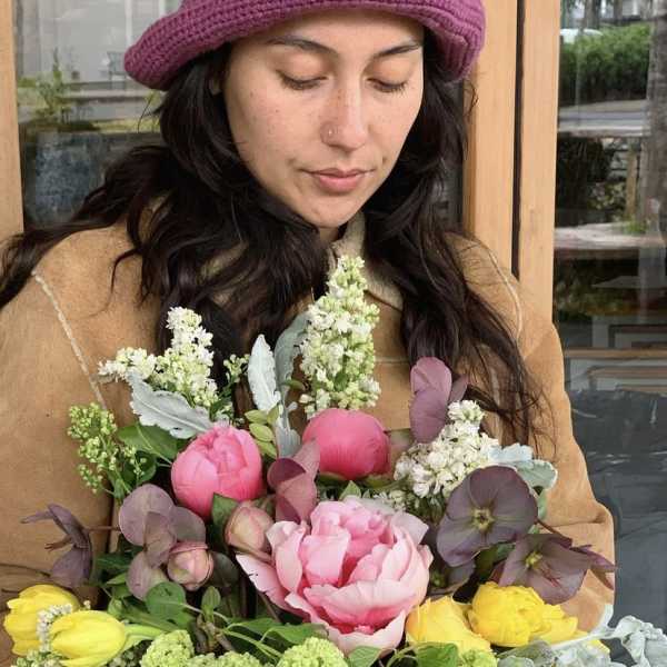 Woman holding a colorful bouquet of pink, yellow, and green flowers