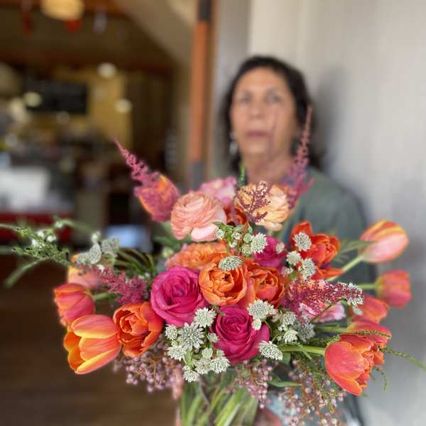 Handheld bouquet of orange, pink, and peach flowers