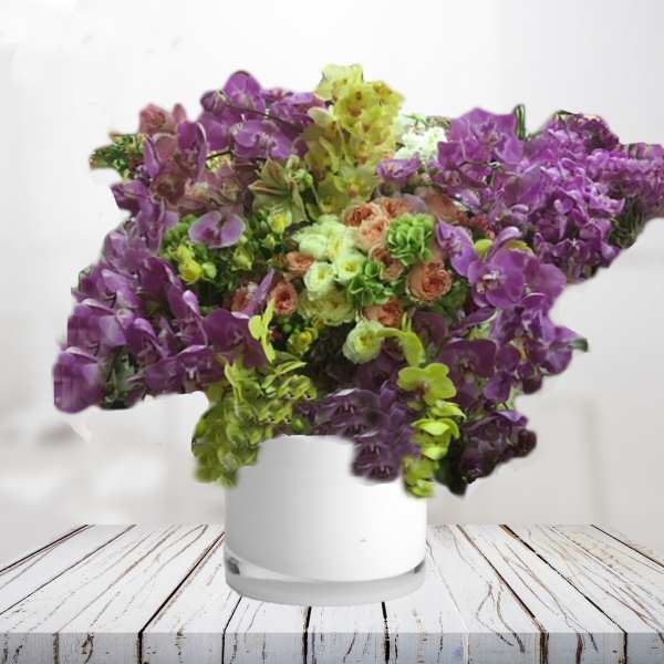 Purple and green orchid arrangement in a white vase