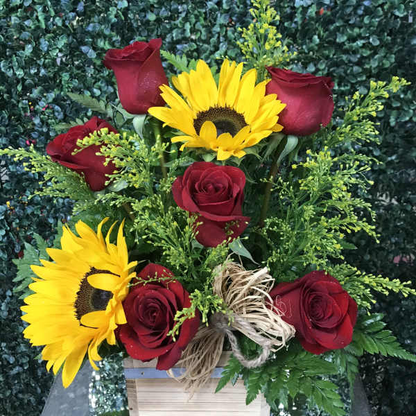 Red roses and yellow sunflowers in a wooden box