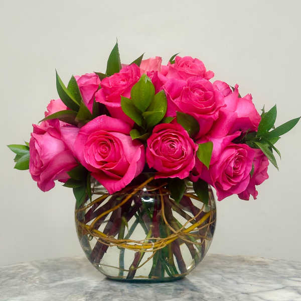 Pink roses arranged in a clear glass bowl vase