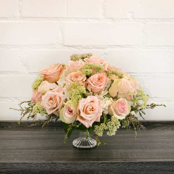 Blush pink roses arranged in a clear glass vase