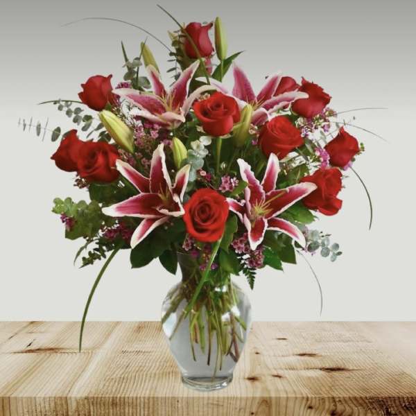 Red roses and pink lilies arranged in a clear glass vase