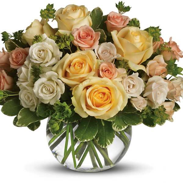Bouquet of cream, peach, and yellow roses in a clear glass vase