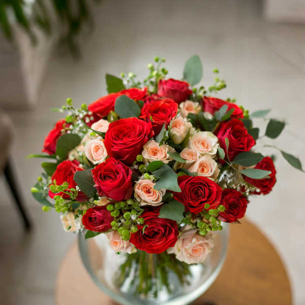 Bouquet of red and blush roses in a clear glass vase