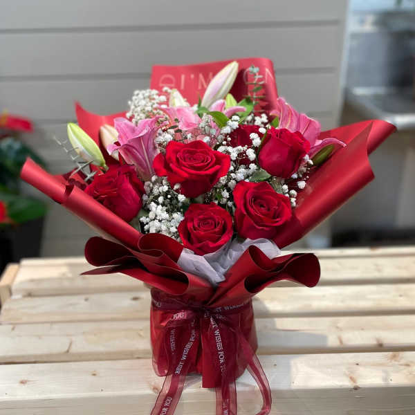 Bouquet of red roses and pink lilies wrapped in red paper