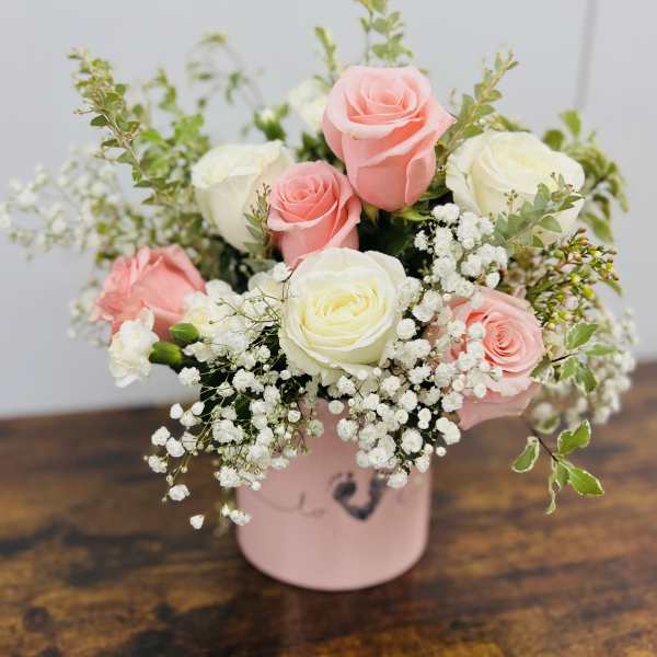 Pink and white roses arranged in a pink box with baby's breath
