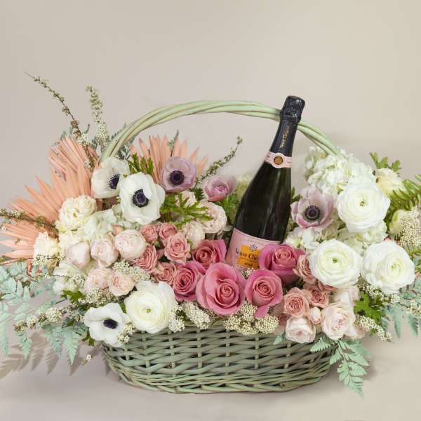Basket of pink and white flowers with a champagne bottle