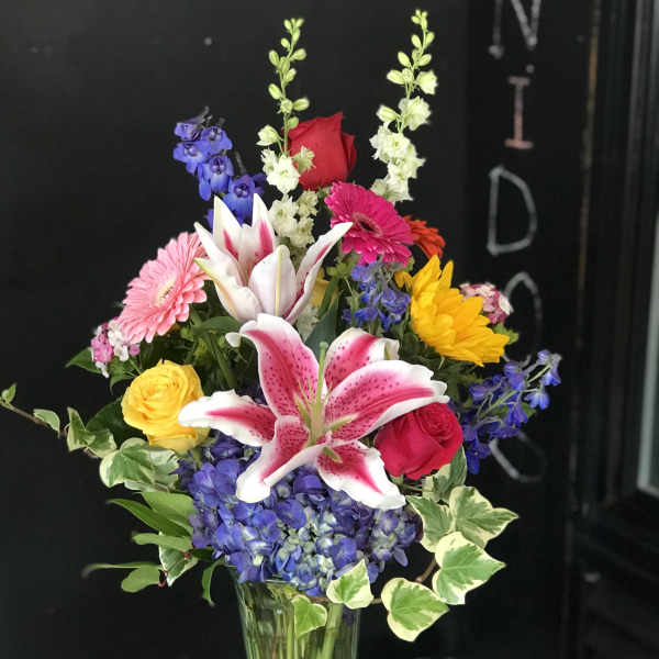 Mixed bouquet in a clear glass vase with lilies, roses, hydrangea, and gerbera daisies