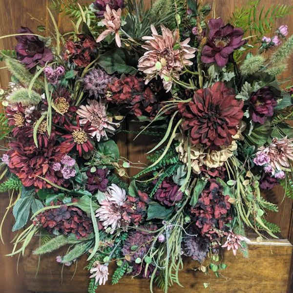 Large floral wreath with burgundy and blush blooms on a wooden door