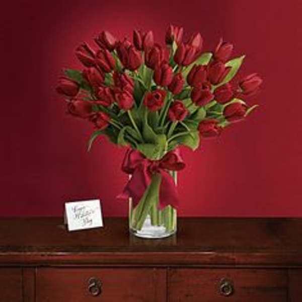 Bouquet of red tulips in a clear glass vase with a ribbon