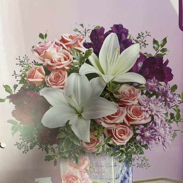 Pink roses, white lilies, and purple flowers in a decorated vase