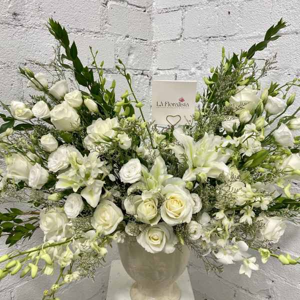 White floral arrangement in a cream urn vase